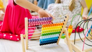 girl holding multi colored wooden abacus